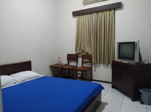 a bedroom with a bed and a tv and chairs at Tiara Puspita Laweyan Hotel in Grogol