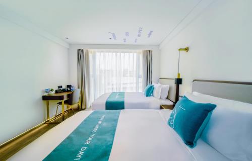 a hotel room with two beds and a window at Pengke Boutique Hotel - Sungang Sunway Station in Shenzhen