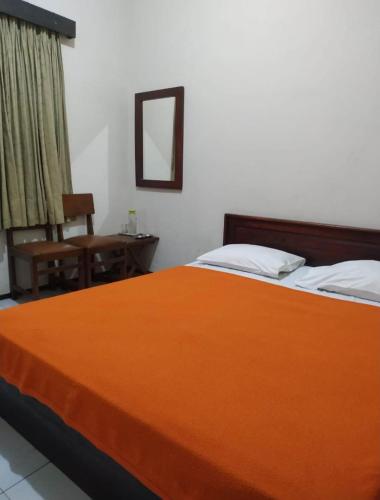 Tiara Puspita Laweyan Hotel في Grogol: غرفة نوم بسرير برتقالي كبير وكرسي