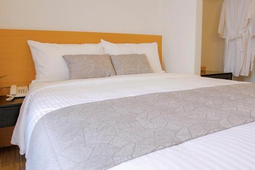 a bedroom with a large bed with white sheets and pillows at Lá Homestay in Mỹ Phước