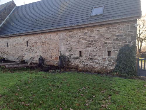 ein Backsteingebäude mit zwei Bänken in einem Hof in der Unterkunft la hamonniere in Savigny-le-Vieux