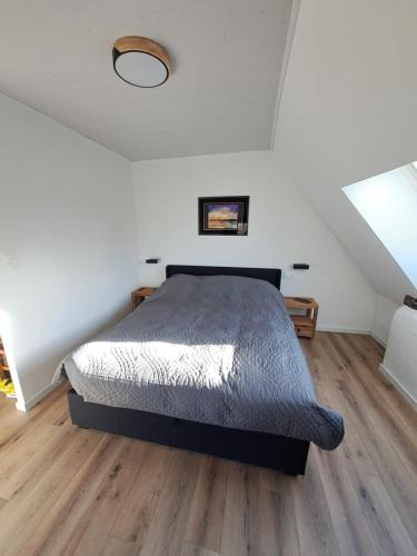 1 dormitorio con 1 cama y suelo de madera en la hamonniere, en Savigny-le-Vieux