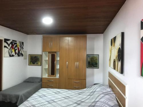 フロリアノポリスにあるApartamento Rafaelliのベッドルーム1室(ベッド1台付)、木製キャビネットが備わります。