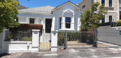 a white fence in front of a white house at Gardens Retreat in Cape Town