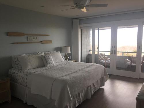 um quarto branco com uma cama e uma varanda em Ship Bottom Oceanfront Condo With Pool! em Ship Bottom