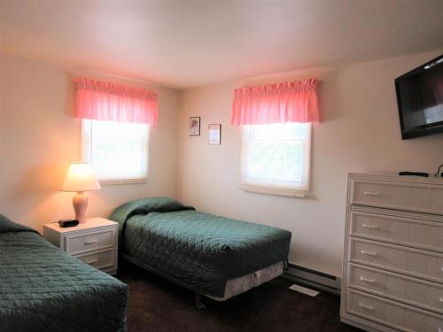 een slaapkamer met 2 bedden, een dressoir en een tv bij 1st Floor Duplex In Brant Beach Just 3 Homes From The Beach in Brant Beach