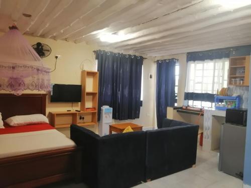 烏昆達的住宿－MAGNOLIA SUITES，一间卧室配有一张床、一张沙发和一台电视。