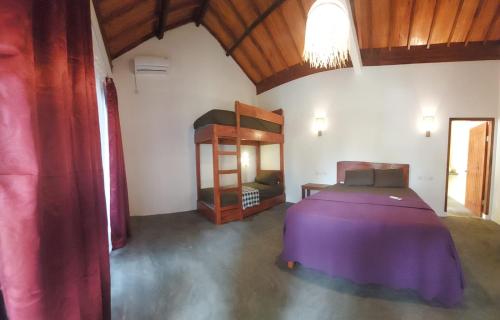 a bedroom with a purple bed and a mirror at Kambuna Bungalow in Krui