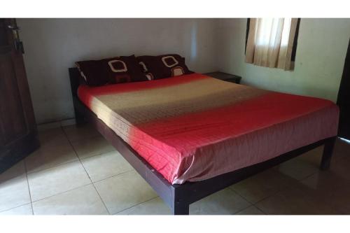 uma cama num quarto com um edredão vermelho em SPOT ON 93524 Bagas Homestay em Lembuak