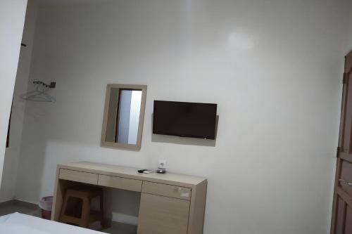 um quarto com uma secretária e uma televisão na parede em OYO 93536 Pondok Almirah em Mamuju
