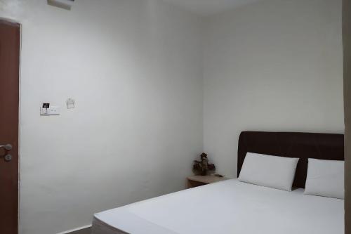 a bedroom with a white bed with a black headboard at OYO 93536 Pondok Almirah in Mamuju