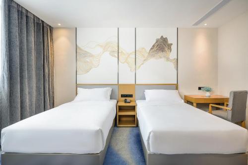 a hotel room with two beds and a desk at Licheng Langyue Hotel - Huizhou Huicheng Shuikou Branch in Huizhou