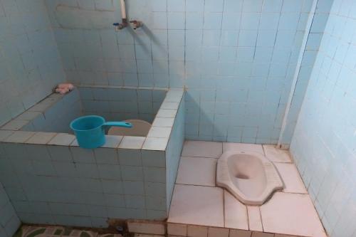een badkamer met een toilet en een blauwe beker bij SPOT ON 93539 Juan Guest House in Purwokerto