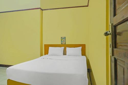 1 cama con 2 almohadas blancas en una habitación en OYO 93523 Penginapan Laras Paminggir, en Rantau