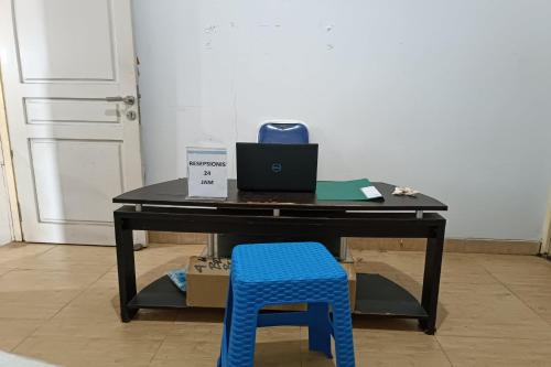 a desk with a laptop computer and a blue stool at Hotel O Wisma Haji BunbunNearYani Heahlerr in Rantau