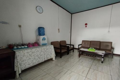 a waiting room with chairs and a table and a clock at Hotel O Wisma Haji BunbunNearYani Heahlerr in Rantau