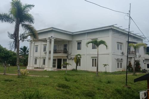 a large white building with palm trees in front of it at Hotel O Umbuy Homestay NearKetupat Kandangan Haji Irus in Rantau