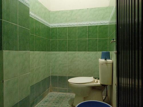 ein Badezimmer mit einem WC und einer grün gefliesten Wand in der Unterkunft OYO 93538 Millow Kost in Parepare