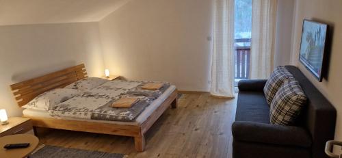 a small bedroom with a bed and a couch at Chata SNOW in Valča