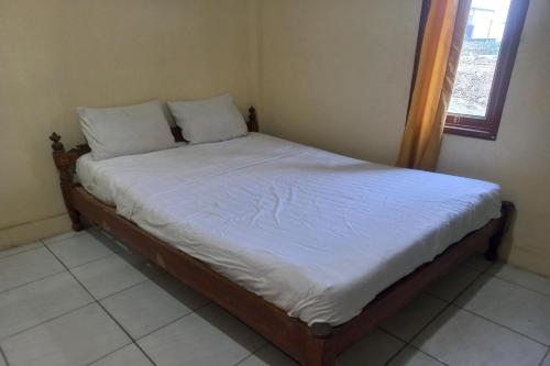 een bed met witte lakens en kussens in een kamer bij SPOT ON 93542 Suripah Kostel Syariah in Banyumas
