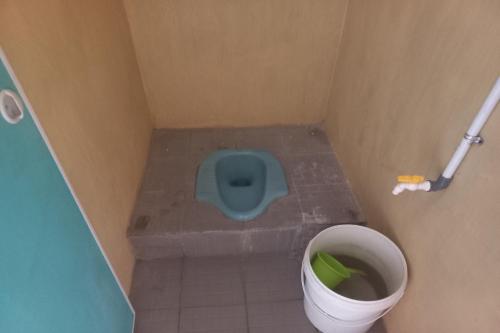 a small bathroom with a blue toilet and a trash can at SPOT ON 93542 Suripah Kostel Syariah in Banyumas