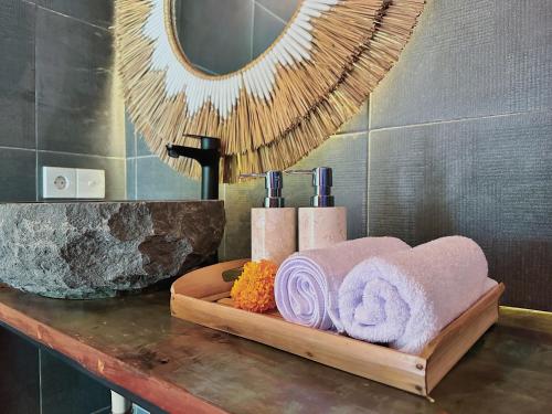a wooden counter with towels and a mirror in a bathroom at Uma Raos Cottage in Ubud