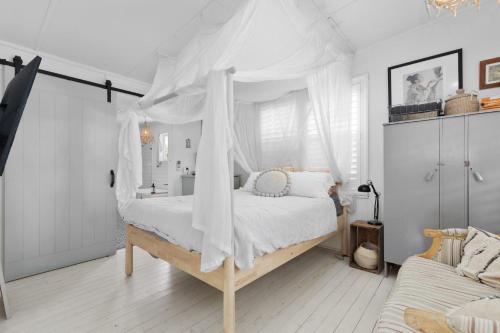 1 dormitorio con 1 cama con dosel en Adrift - Pet-friendly - 5 min Walk to Bay - Rustic Charm, en Erowal Bay