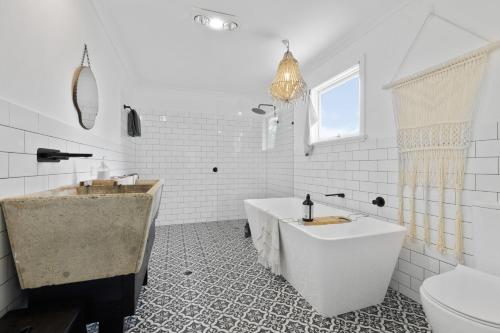 a white bathroom with a tub and a sink at Adrift - Pet-friendly - 5 min Walk to Bay - Rustic Charm in Erowal Bay