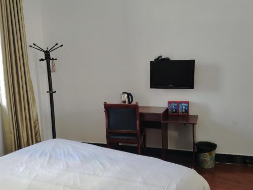 a bedroom with a desk and a tv and a bed at 张家界大庸家民宿天门山索道站店DYJ Residential hostel in Zhangjiajie