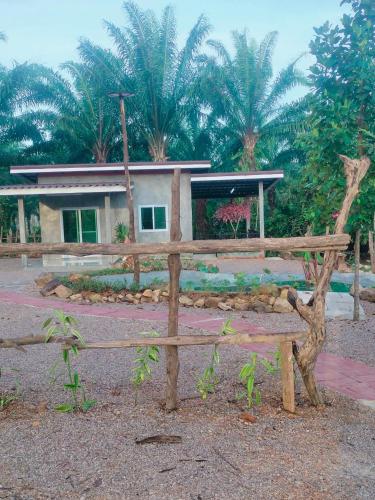 a wooden bench in front of a house with palm trees at Baan Namthip Homestay Trang บ้านน้าทิพย์ โฮมสเตย์ตรัง in Ban Huai To (1)