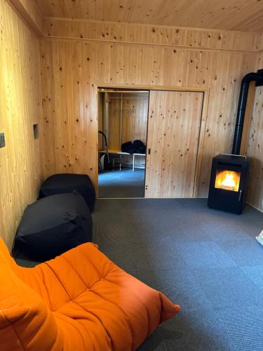 an empty room with an orange couch and a fireplace at NIKONOS III in Nozawa Onsen