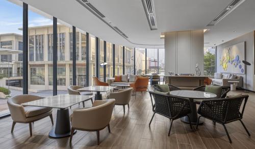 a restaurant with tables and chairs and large windows at Hyatt Place Kuala Lumpur Bukit Jalil in Kuala Lumpur