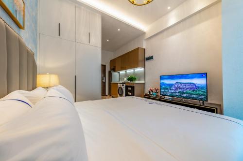 a bedroom with a large white bed and a flat screen tv at BORUISI Plaza Residence Apartment - Shenzhen Futian Convention & Exhibition Center in Shenzhen