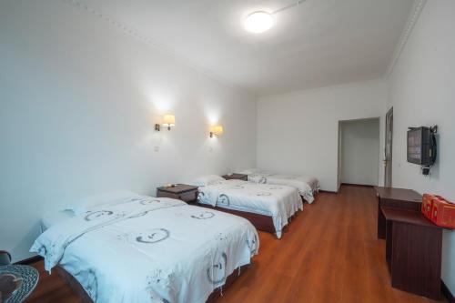 a room with three beds and a flat screen tv at 张家界大庸家民宿天门山索道站店DYJ Residential hostel in Zhangjiajie