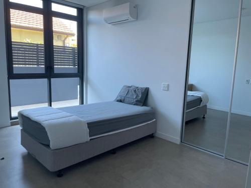 a small bedroom with a bed and a mirror at Unit 103, 1-5 Oxford Street, Blacktown, NSW 2148 in Blacktown
