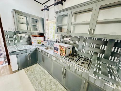 a kitchen with blue cabinets and a stove top oven at Villa Beach Heaven in Hikkaduwa