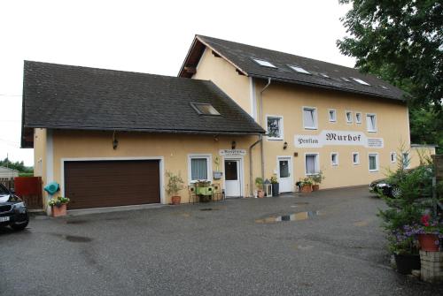 a building with a garage and a car parked in front at Pension Murhof in Gössendorf