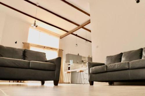 two black leather couches in a living room at Enkai Farmhouse near Ol-Pejeta Nanyuki in Nanyuki