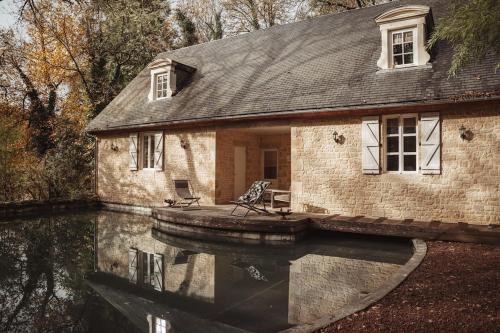 an old stone house with a reflection in the water at Cabane Rouge-Gorge in Auriac-du-Périgord