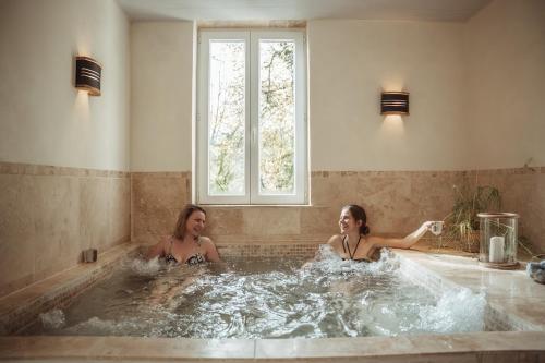 zwei Frauen in einer Whirlpool-Badewanne mit Fenster in der Unterkunft Cabane Rouge-Gorge in Auriac-du-Périgord