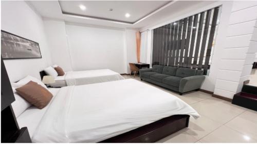 a hotel room with two beds and a couch at Phuong Dong Hotel and Apartment in Quy Nhon