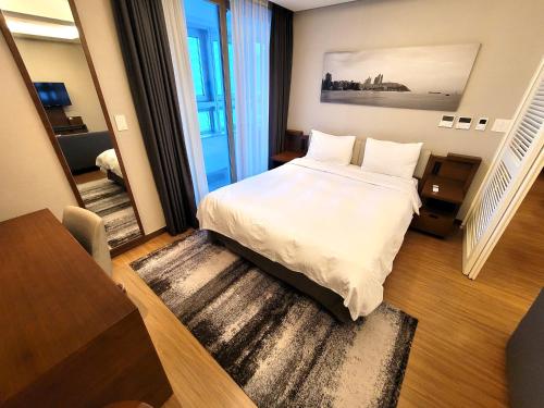 Un dormitorio con una gran cama blanca y una escalera en W Residence Hotel, en Busan