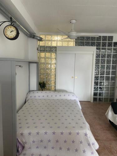 Un dormitorio con una cama y un reloj en la pared. en ESTUDIO EN SANJOSE A 50 M DE LA PLAYA, en San José
