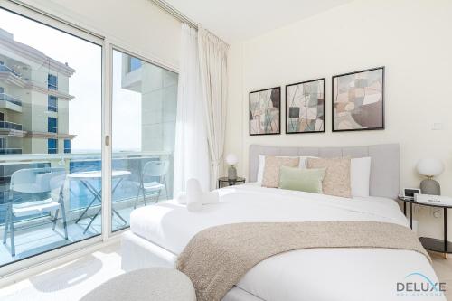 a bedroom with a white bed and a large window at Comfortable Studio at Lago Vista A Dubai Production City by Deluxe Holiday Homes in Dubai