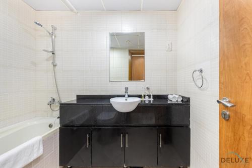 a bathroom with a sink and a tub and a mirror at Comfortable Studio at Lago Vista A Dubai Production City by Deluxe Holiday Homes in Dubai