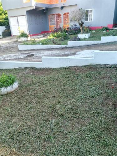 a yard with grass and a house with a building at Cozy Guest Room in Port Antonio