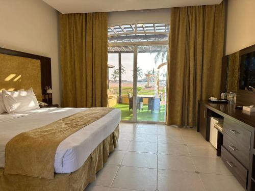 a hotel room with a bed and a large window at Samharam Resort Salalah in Salalah