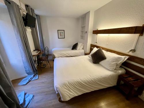 a hotel room with two beds and a television at Hotel Restaurant Le Clos in Besse-et-Saint-Anastaise