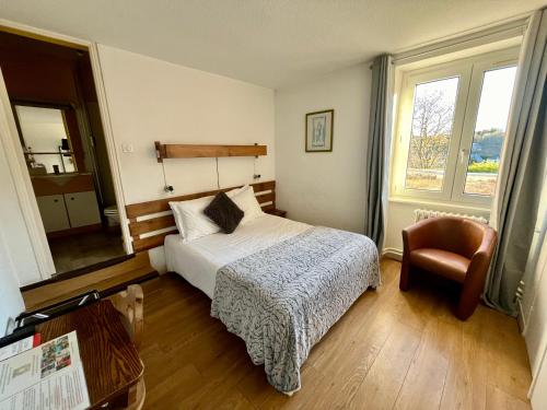 een slaapkamer met een bed, een stoel en een raam bij Hotel Restaurant Le Clos in Besse-et-Saint-Anastaise