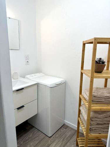 - une cuisine blanche avec évier et étagère dans l'établissement “Le Terracotta” Terrasse -Centre ville- Cosy, à Bourg-en-Bresse